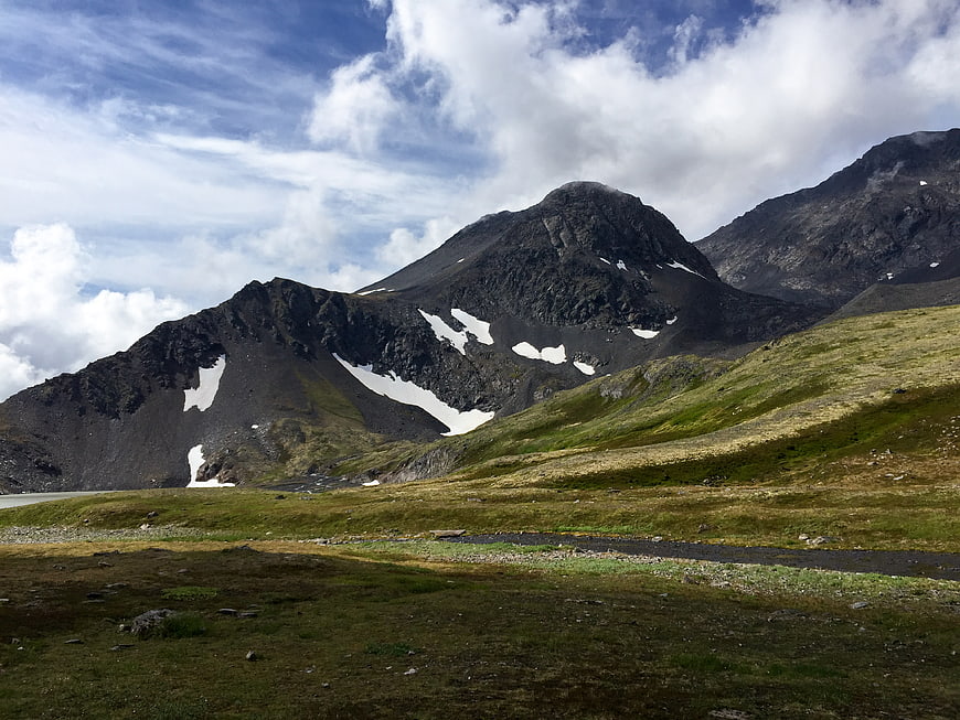Scenic mountain landscape with snow patches and green meadow