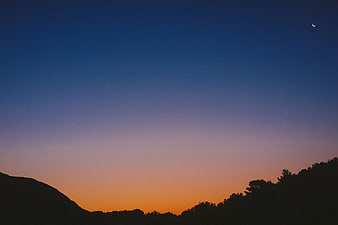 Crescent Moon Over Silhouetted Hills at Sunset