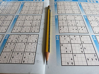Yellow pencil on open sudoku puzzle book