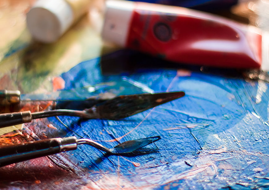 Close-up of artist palette with palette knives and paint tubes
