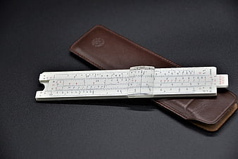 Vintage Ariti Slide Rule and Brown Leather Case on Dark Background