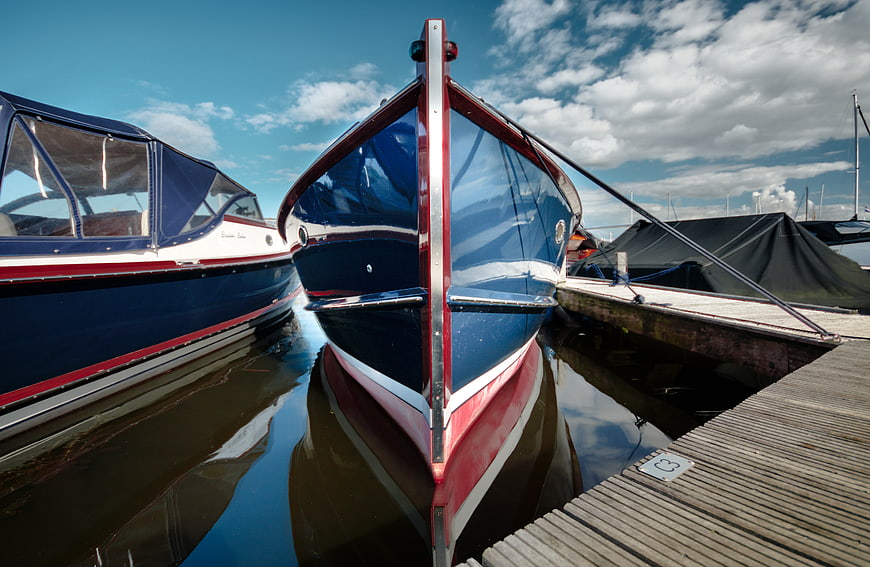 Blue and red boat docked at wooden pier