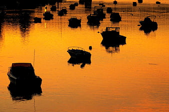 Silhouetted boats on golden water at sunset