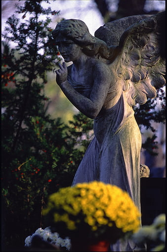 Weathered Stone Angel Statue in Cemetery with Flowers