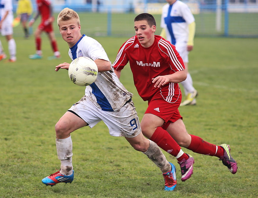 Two young soccer players competing for the ball on a grass field