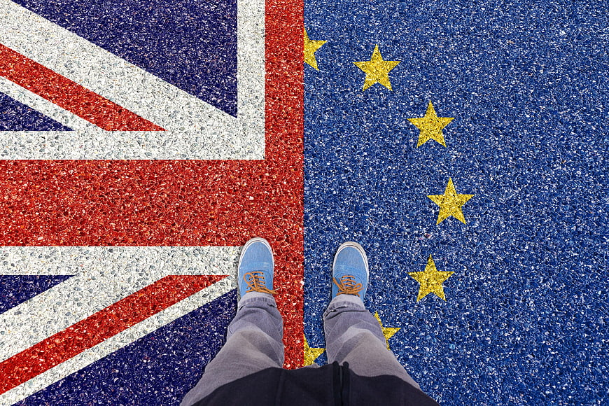 Person standing on painted UK and EU flags on asphalt