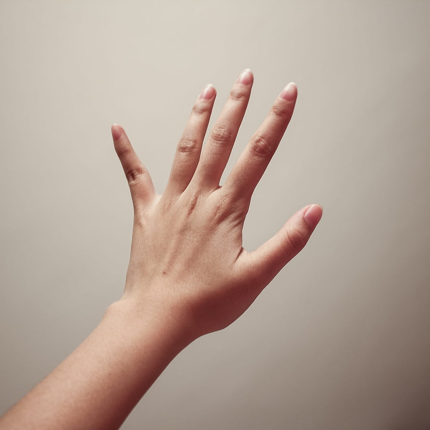 Close-up of a human hand reaching up against a beige background