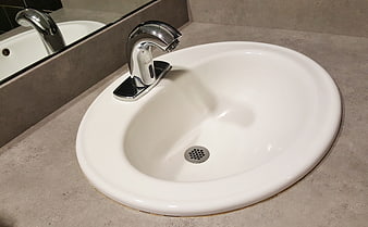 Modern white bathroom sink with chrome faucet on gray countertop