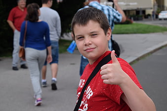 Cute boy giving thumbs up on street