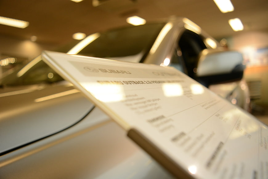 Subaru Outback price tag on car hood in dealership showroom
