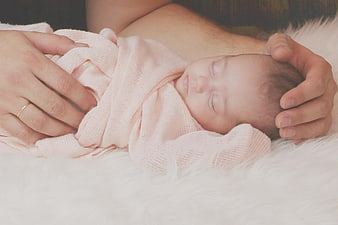 Newborn baby sleeping peacefully wrapped in pink blanket
