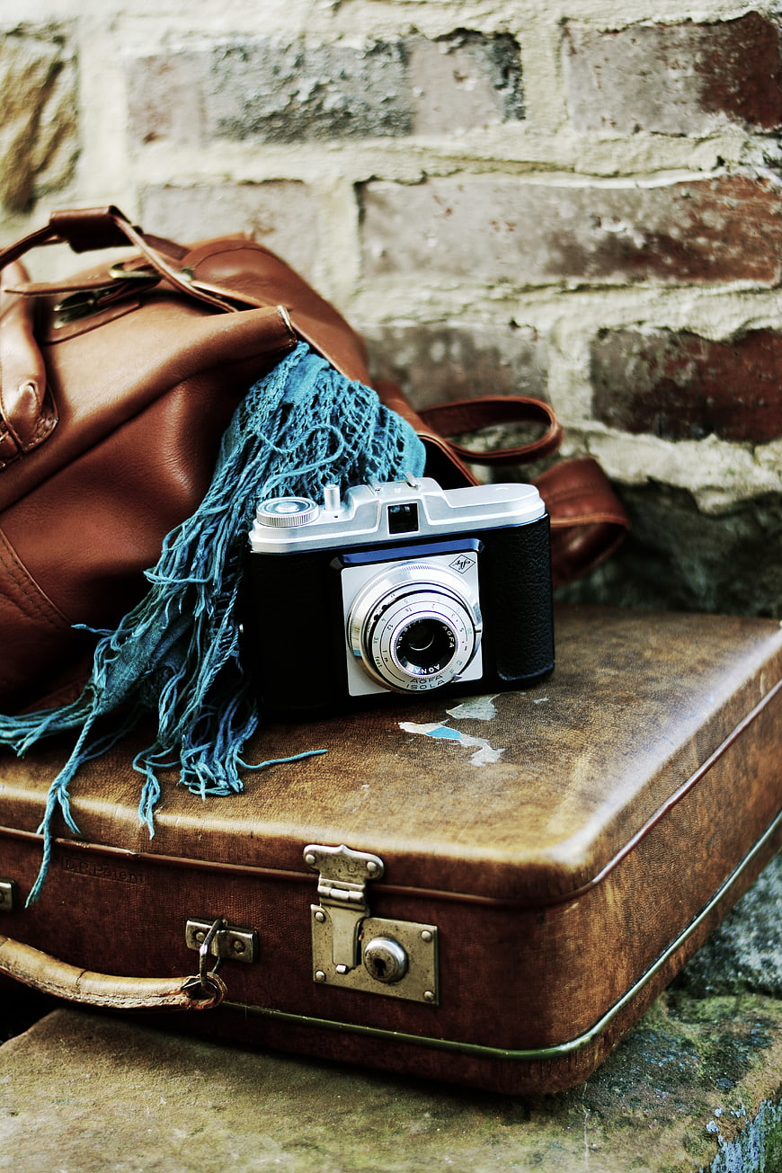 Vintage Camera and Leather Suitcase on Brick Wall