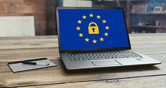 Laptop Displaying EU Flag and Lock Icon on Wooden Desk