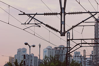 Overhead Railway Catenary System Against Urban Skyline At Dusk