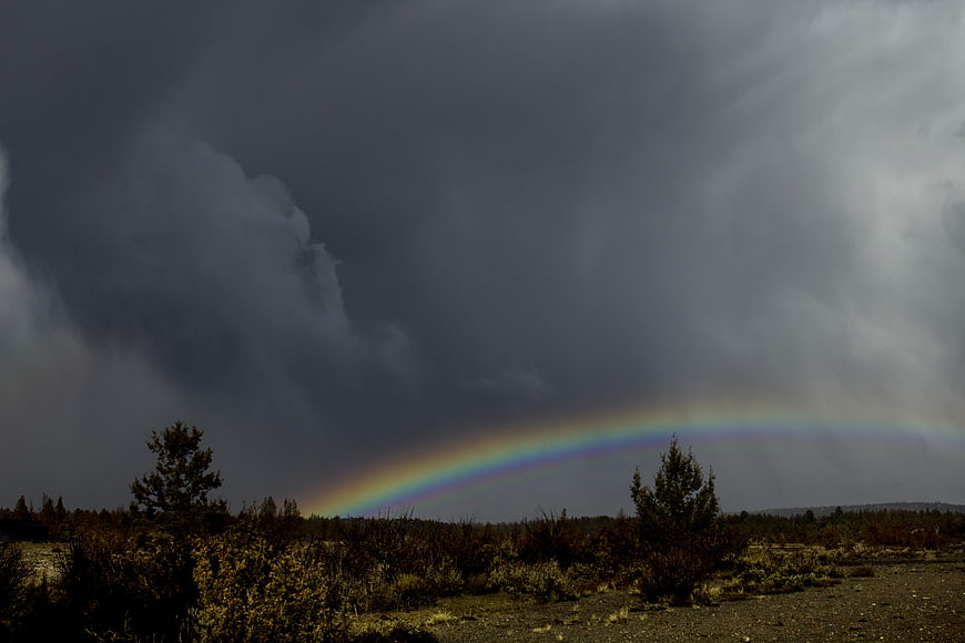 Vibrant Rainbow Arching Over Stormy Desert Landscape