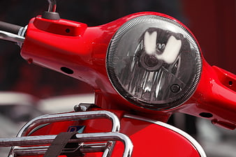 Close-up of red scooter headlight and handlebars
