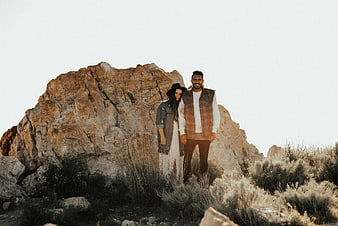 Couple standing in front of large rock formation outdoors