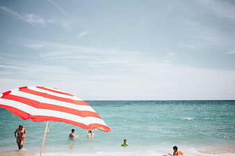 Red and white striped beach umbrella with ocean background
