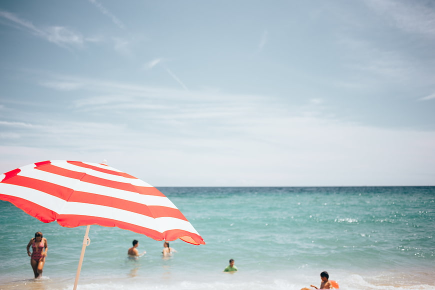 Red and white striped beach umbrella with ocean background