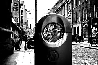 Black and white street photography of a man framed by a bollard