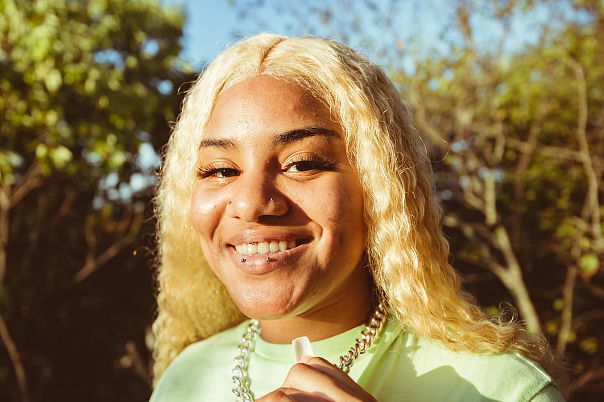 Smiling woman with blonde hair outdoors in sunlight