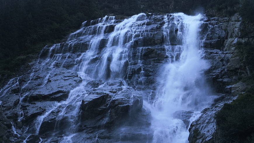 Majestic cascading waterfall flowing over dark rocky cliffs