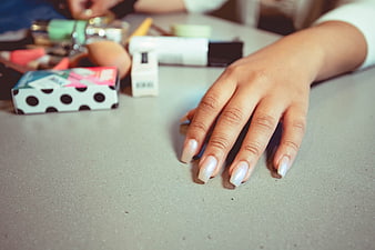 Close-up of female hand with white manicure on table