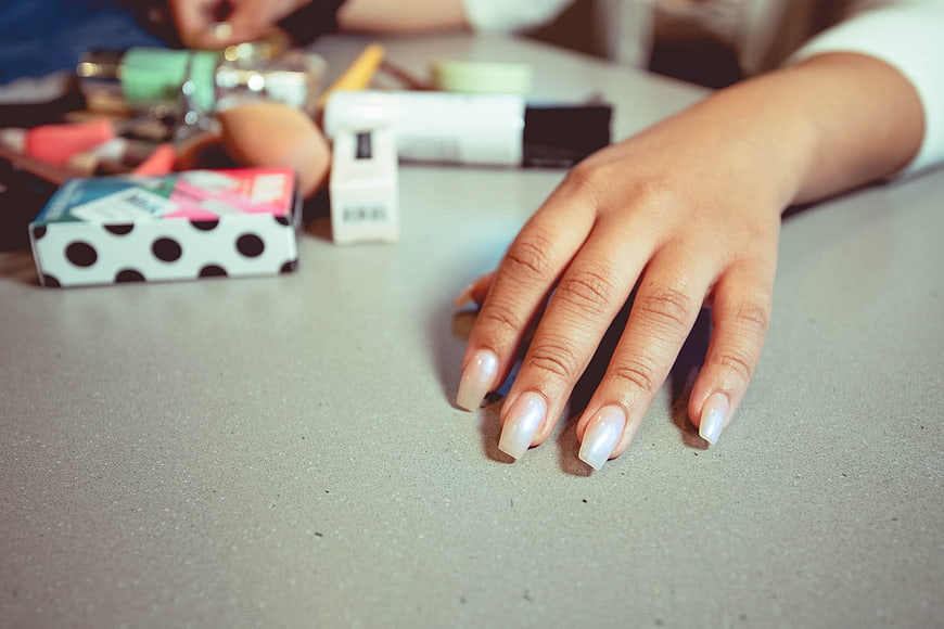Close-up of female hand with white manicure on table