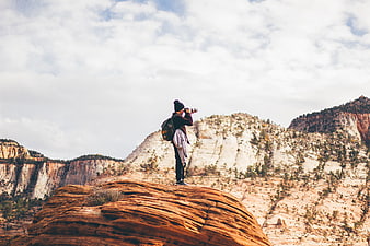 Photographer with camera standing on red rock formation