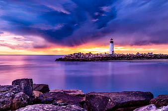 Dramatic Lighthouse Sunset Over Smooth Ocean Waters