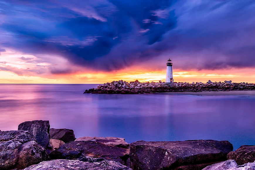 Dramatic Lighthouse Sunset Over Smooth Ocean Waters