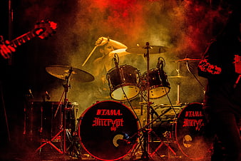 Energetic Drummer Performing on Stage with Red Lighting