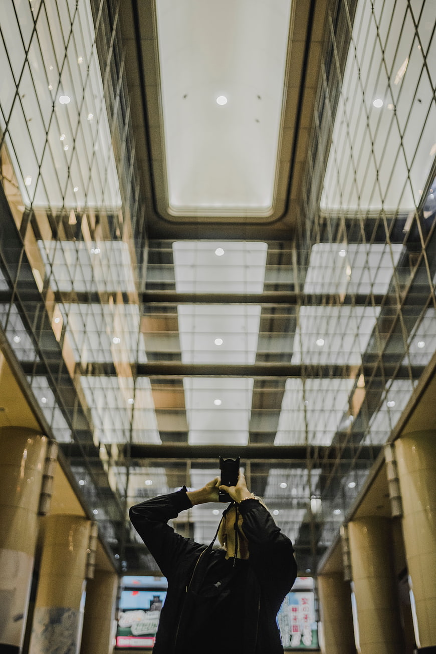 Low angle view of photographer capturing modern glass ceiling architecture