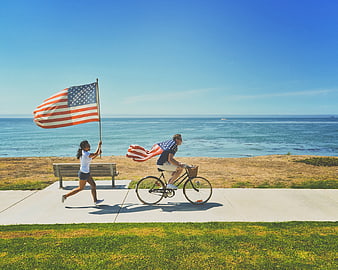 Couple celebrating with American flags on coastal bike path
