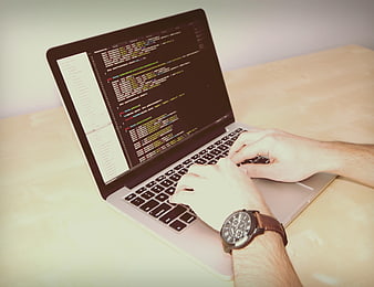 Hands typing code on laptop with watch