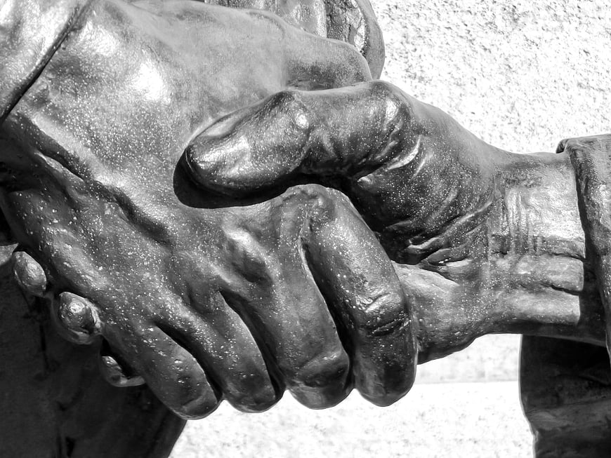 Close-up of bronze statue hands clasped in agreement