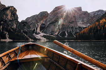Wooden Rowboat on Mountain Lake with Sunburst