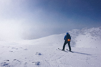 Backcountry skier standing on snowy mountain ridge