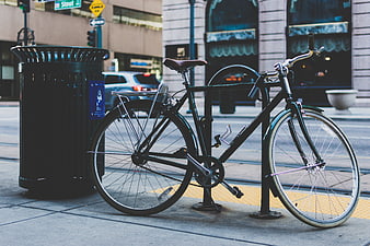 Black bicycle locked to rack on urban city street