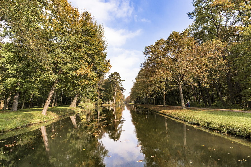 Serene Canal Flanked by Autumn Trees with Reflections