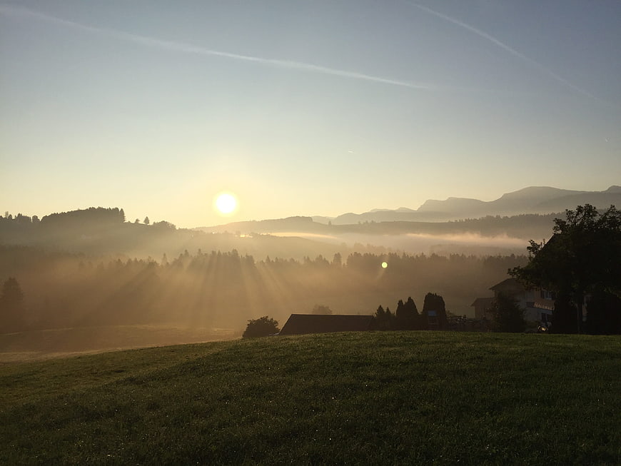 Sunrise over misty valley with sunbeams and rolling hills