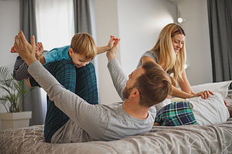 Happy family playing together on bed in bedroom