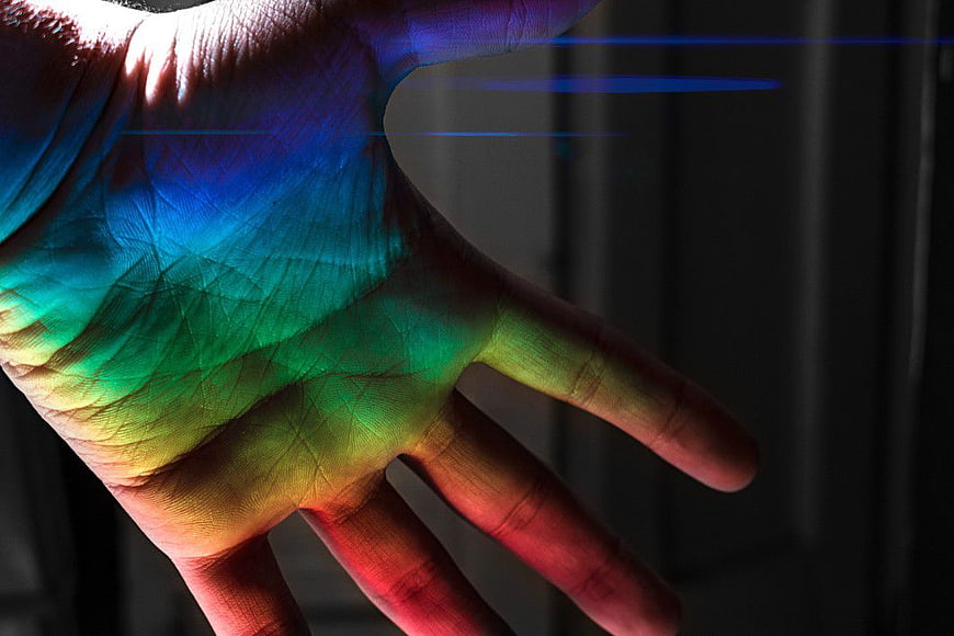 Close-up of hand with vibrant rainbow light projection