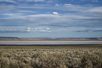 Vast arid landscape with sagebrush, lake, and distant mesas