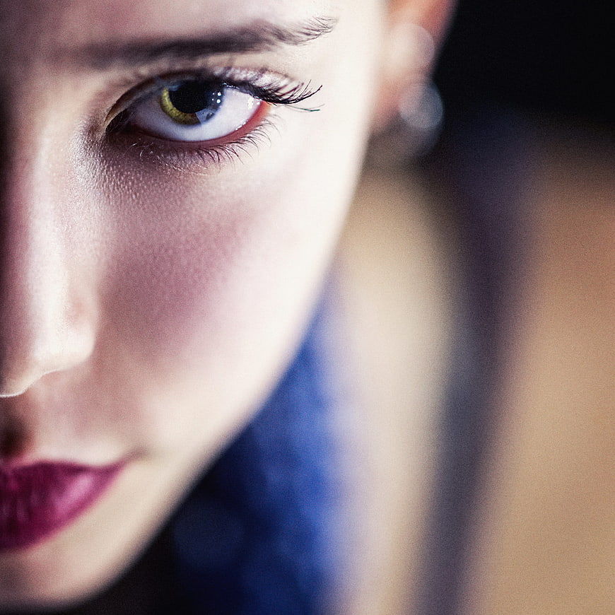 Close-up portrait of woman with striking eye and blue hair