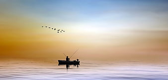 Silhouette of a fisherman in a boat on a calm lake at sunset
