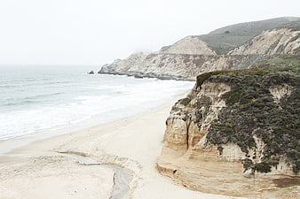 Misty coastal cliffs and sandy beach landscape