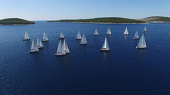 Aerial view of sailboats on deep blue sea near islands