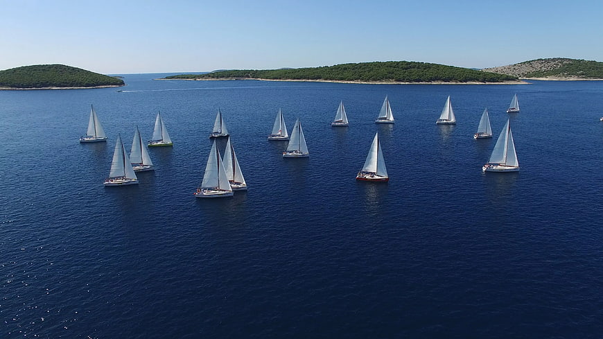 Aerial view of sailboats on deep blue sea near islands