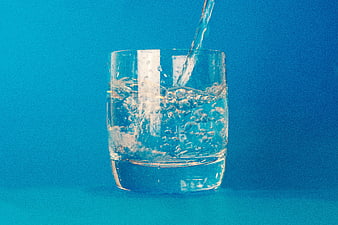 Water Pouring into Glass on Blue Background